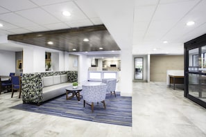 Un intérieur moderne avec un espace salon, un comptoir d’accueil et une cuisine en arrière-plan.