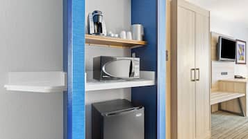 Una kitchenette equipada con microondas, cafetera y estantes para guardar objetos.