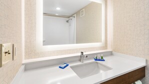 Une salle de bain avec un grand miroir, un lavabo et une douche.