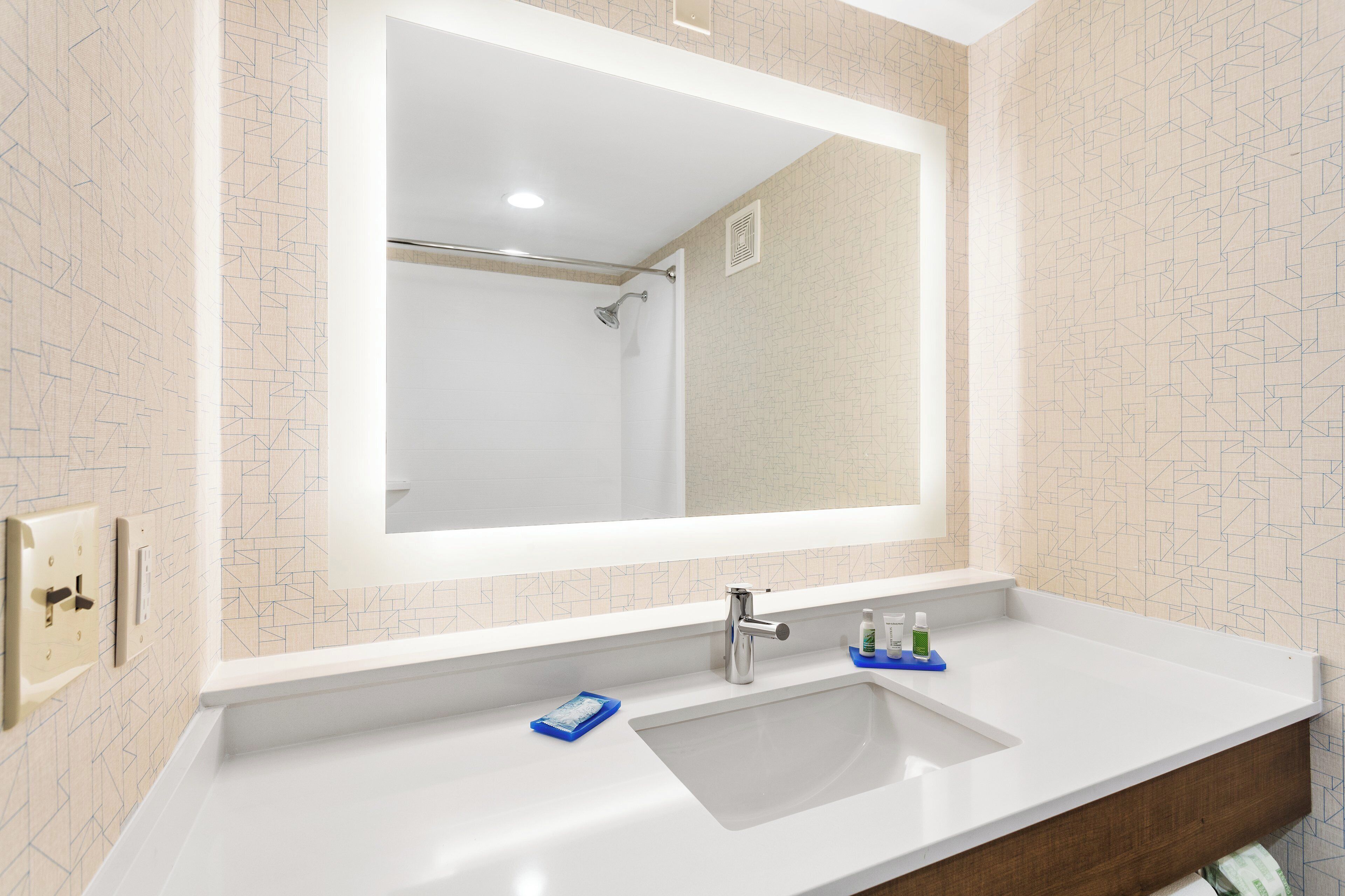 Een badkamer met een wit wastafelmeubel, een spiegel en een douche.