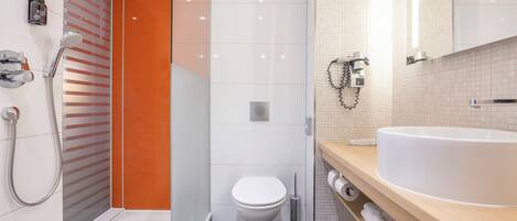 Un baño moderno con ducha de vidrio, inodoro blanco y un lavamanos grande con espejo arriba.