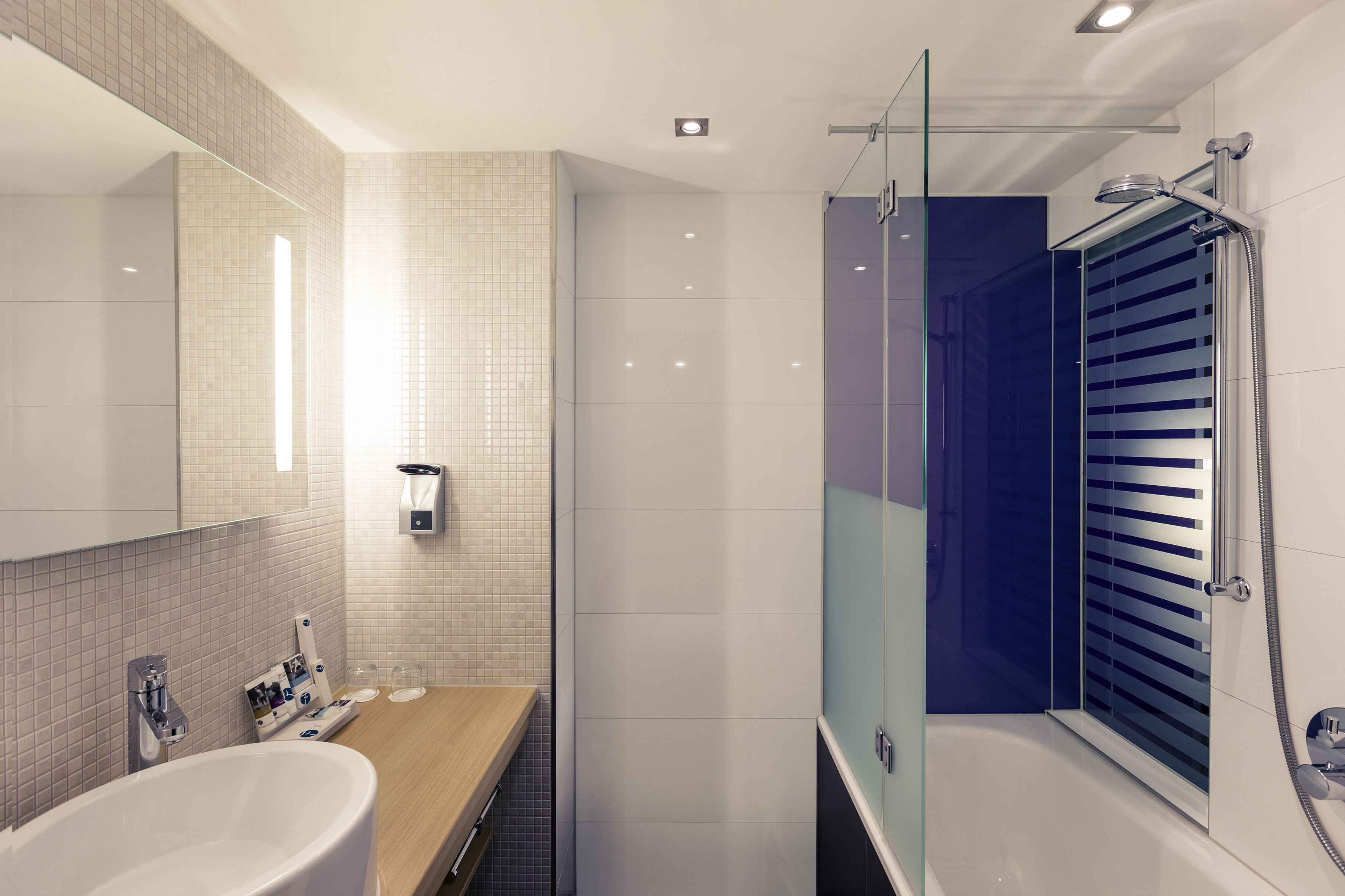 Un baño moderno con una bañera independiente, ducha con cerramiento de vidrio y tocador con espejo y perchero.