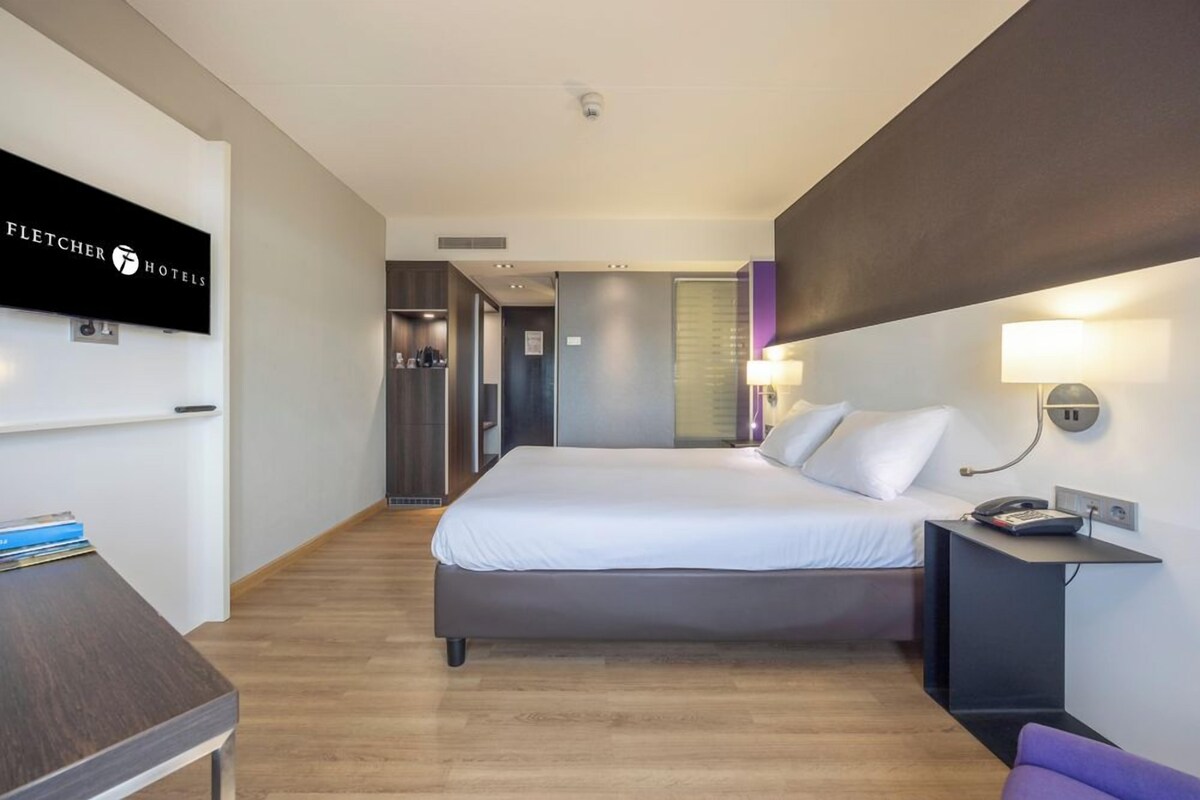 Une chambre d’hôtel équipée d’un lit, d’une table de chevet, d’une lampe et d’un téléviseur fixé au mur.