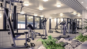 Un gimnasio moderno con diversos equipos de ejercicio, espejos amplios y un jardín de rocas con helechos.
