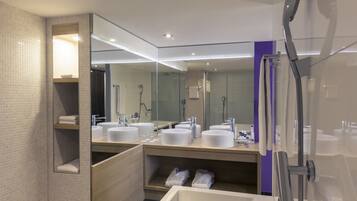 Un baño moderno con dos lavamanos, un espejo grande y una zona de ducha.