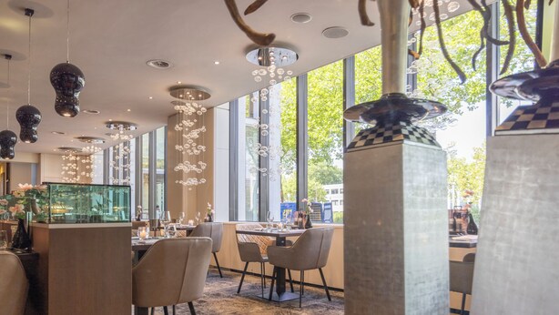 Un comedor moderno con ventanas amplias, luminarias contemporáneas y una mesa central.