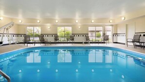Una piscina interior con agua cristalina, rodeada de sillones de descanso y una cama de sol.