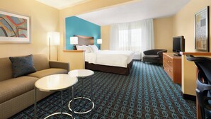 Una habitación de hotel con cama, sofá, escritorio, silla y una mesita.