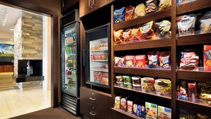 Una presentación de aperitivos con diferentes alimentos envasados y un refrigerador lleno de bebidas.