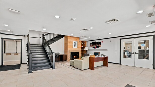A spacious lobby with a staircase, a fireplace, a reception desk, and a seating area. - Willow Inn Suites Rochester (Rochester)