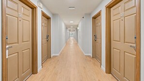 A long, narrow hallway with wooden doors on both sides, each marked with a number. - Willow Inn Suites Rochester (Rochester)