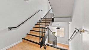 A staircase with wooden steps and black railings, leading to a landing with a window and a door. - Willow Inn Suites Rochester (Rochester)