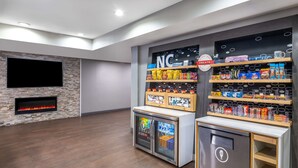 A modern room with a stone fireplace, a flat-screen TV, and a snack vending machine. - Hampton Inn Sanford (Sanford)