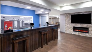 A reception area with a blue wall, a stone fireplace, and a flat-screen TV mounted on the wall. - Hampton Inn Sanford (Sanford)