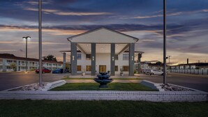 A hotel with a central fountain, a covered entrance, and a parking lot.