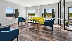 Un salón amplio con un sofá amarillo, sillones azules y una mesa de centro.