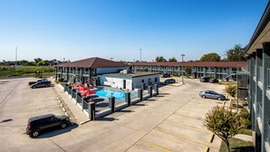 Un hotel con piscina, varios espacios de estacionamiento y un edificio de techo marrón.
