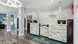 A reception area with a modern design, featuring a reception desk, a wall-mounted sign, and a patterned floor mat.
