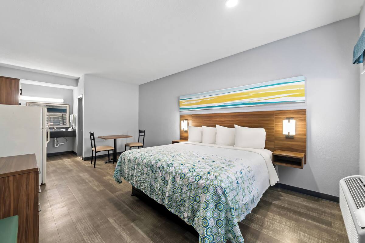 Una habitación de hotel con una cama grande, un escritorio, una silla y una mesita.