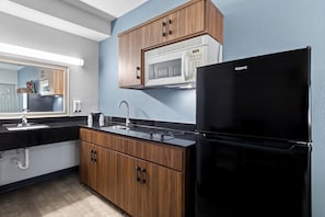 Una cocina moderna con armarios de madera, un refrigerador negro, un microondas y un lavamanos.