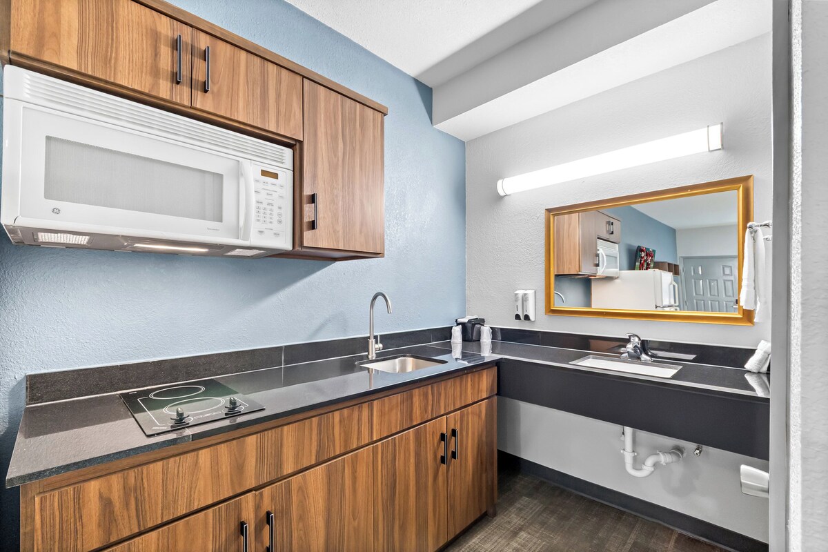 Una cocina moderna con microondas, lavamanos y armarios de madera.