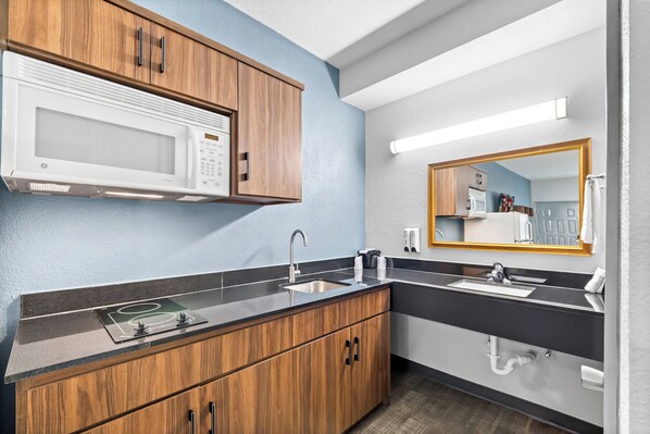 A modern kitchen with a microwave, sink, and wooden cabinets.