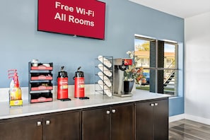 A hotel room with a coffee station, a sign indicating free Wi-Fi, and a window with a view of the outside. - HomeTowne Studios by Red Roof San Antonio E - Frost Bank Center (San Antonio)