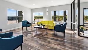 A spacious living room with a yellow sofa, blue chairs, and a coffee table.