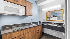 A modern kitchen with a microwave, sink, and wooden cabinets.