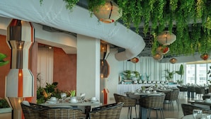 Un restaurant amb plantes d'interior, llums penjants i diferents disposicions de seients.