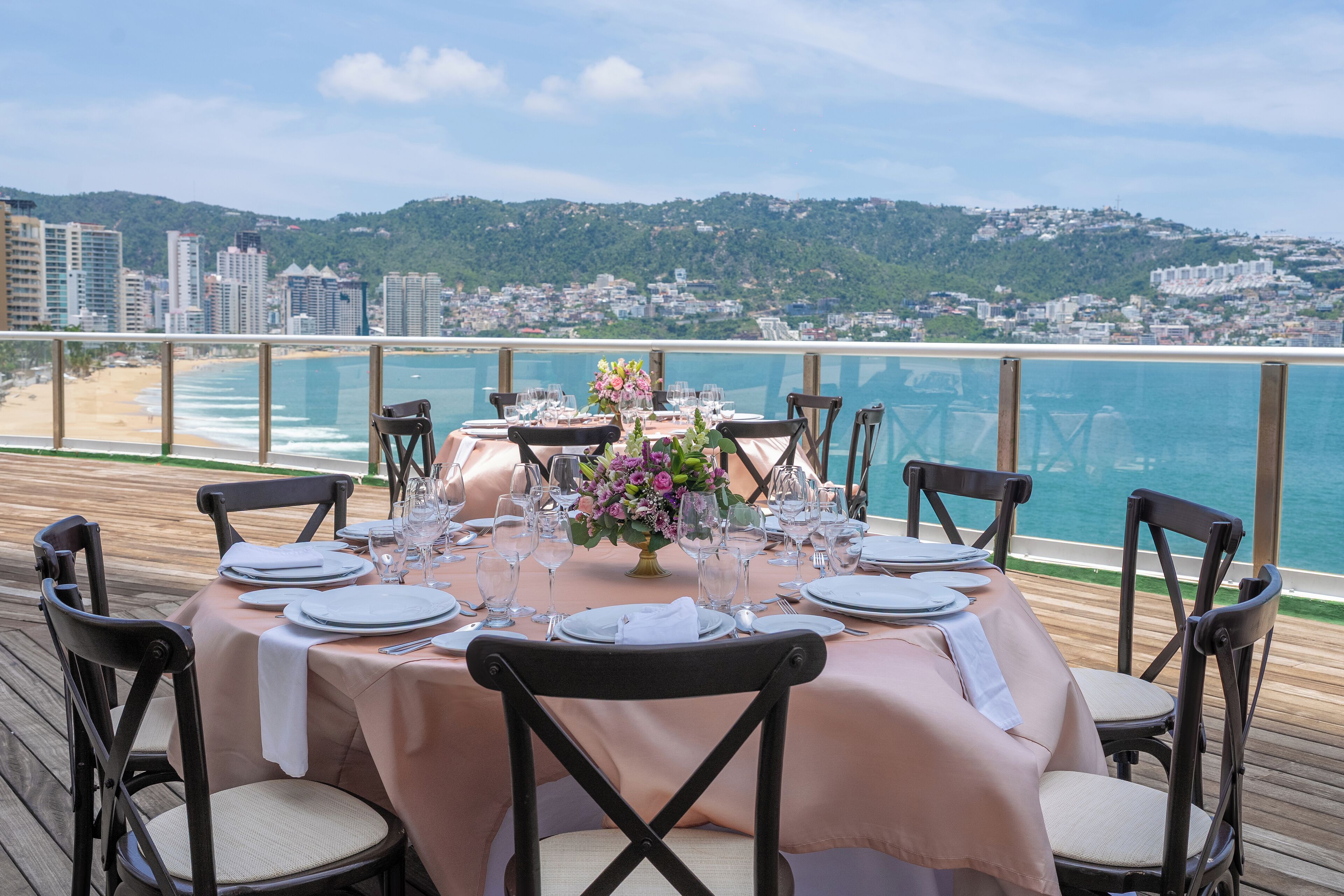 A table set for six with a view of the beach and city in the background.