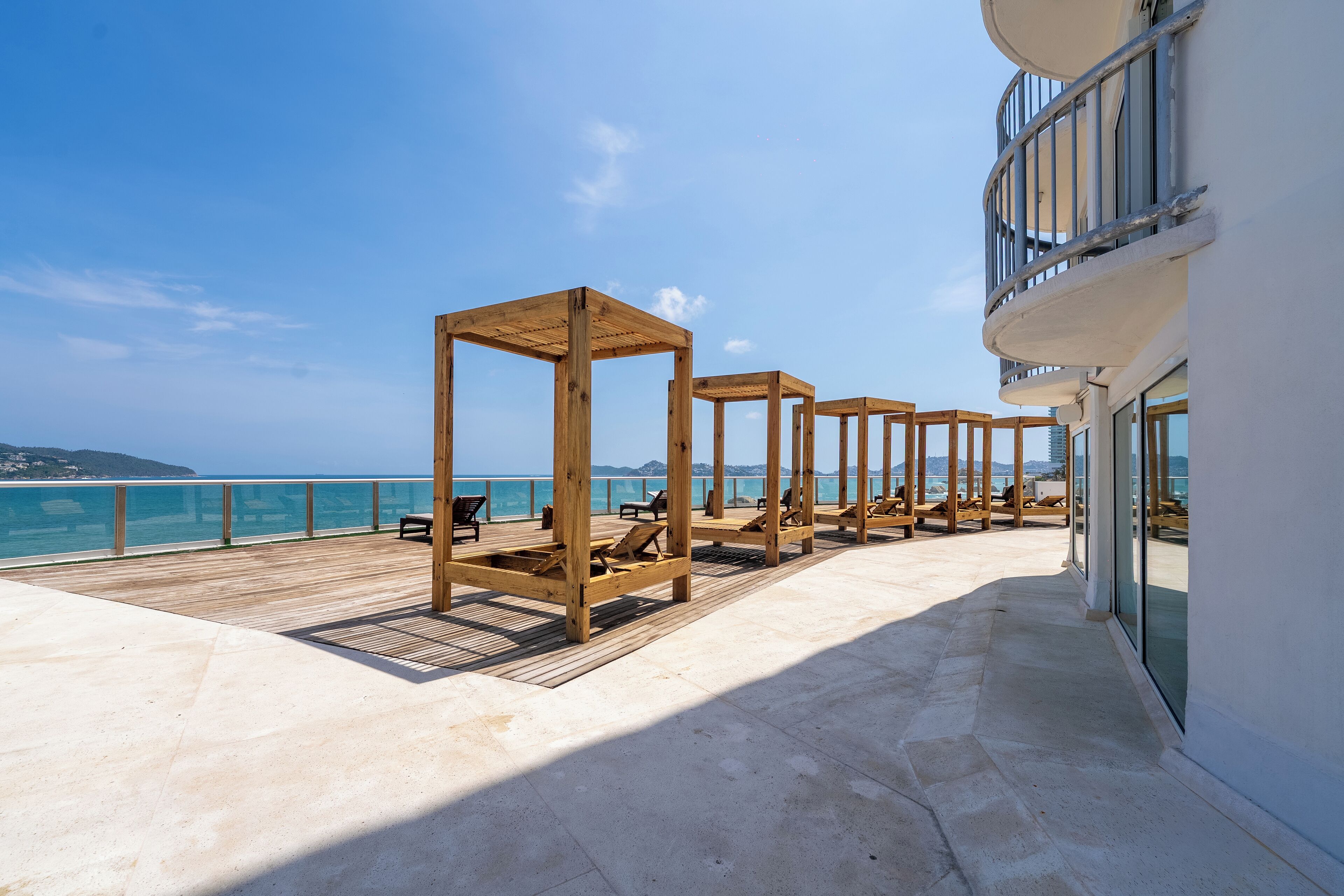 A deck with wooden loungers and a balcony overlooking the sea.