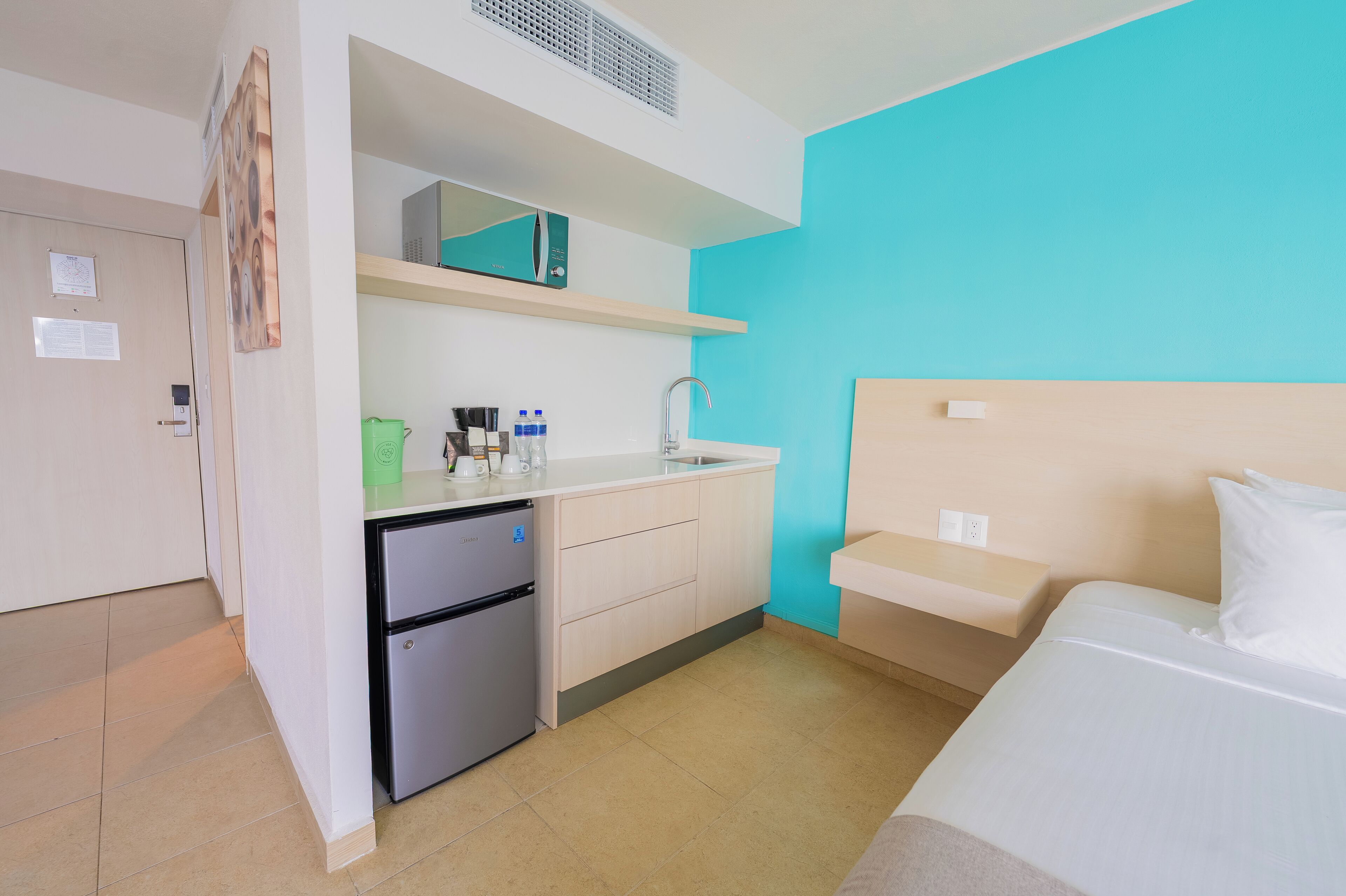 Une chambre d’hôtel de taille réduite, dotée d’une kitchenette, d’un lit et d’une salle de bain.