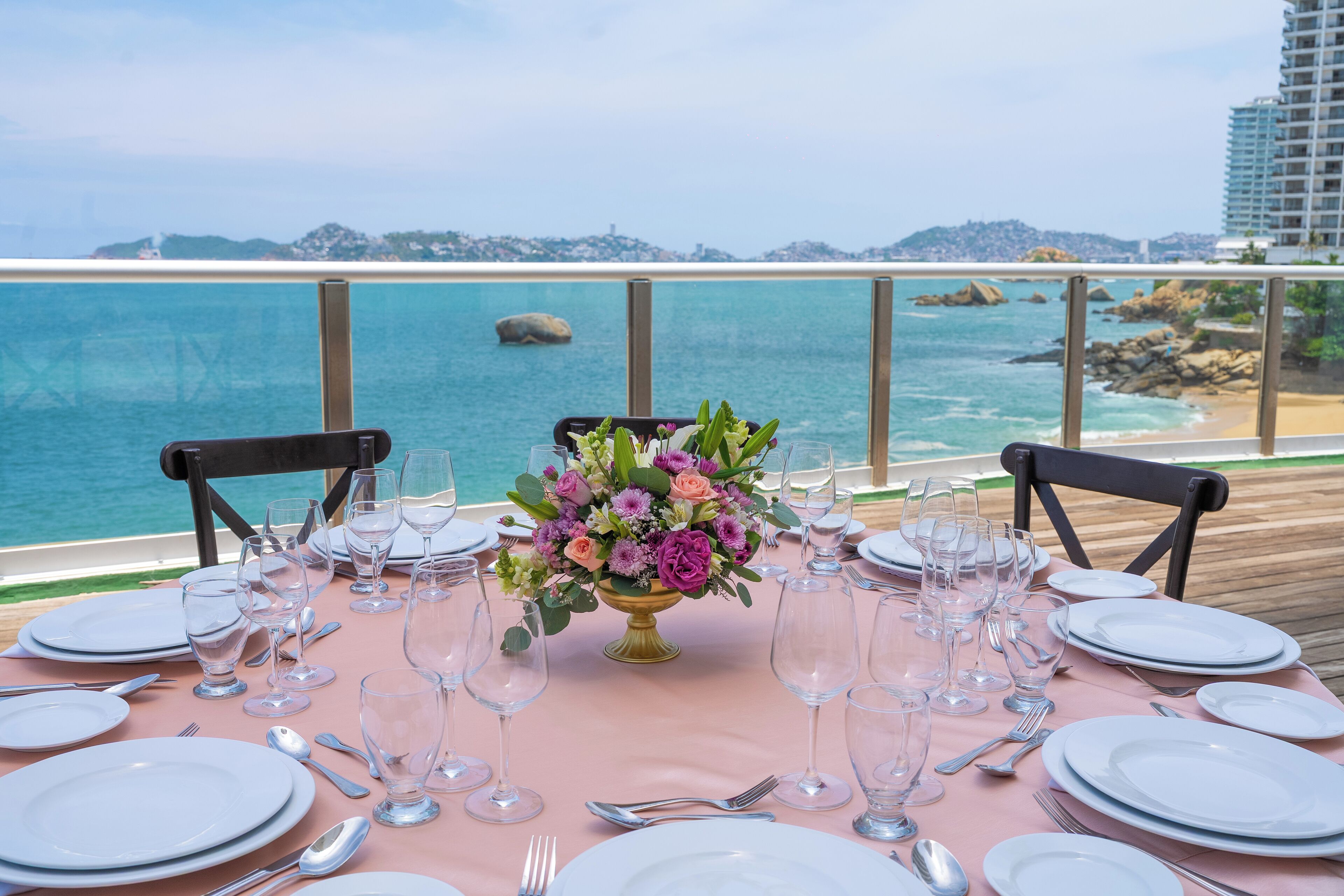 A table set for a meal with a view of the ocean and a cityscape in the background.
