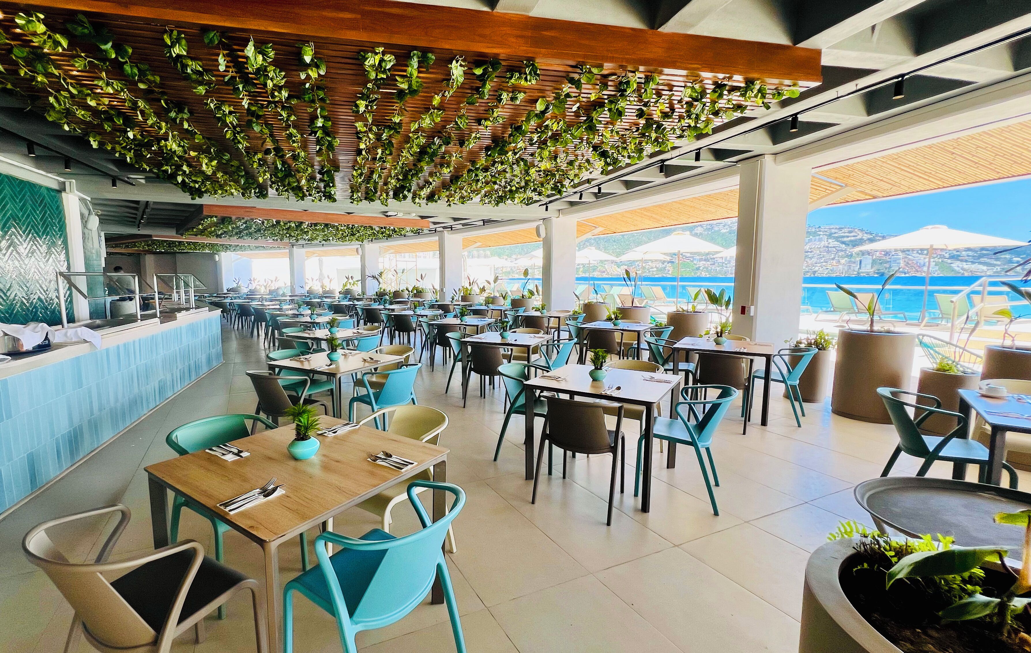 An indoor dining area with tables and chairs, a counter, and potted plants.