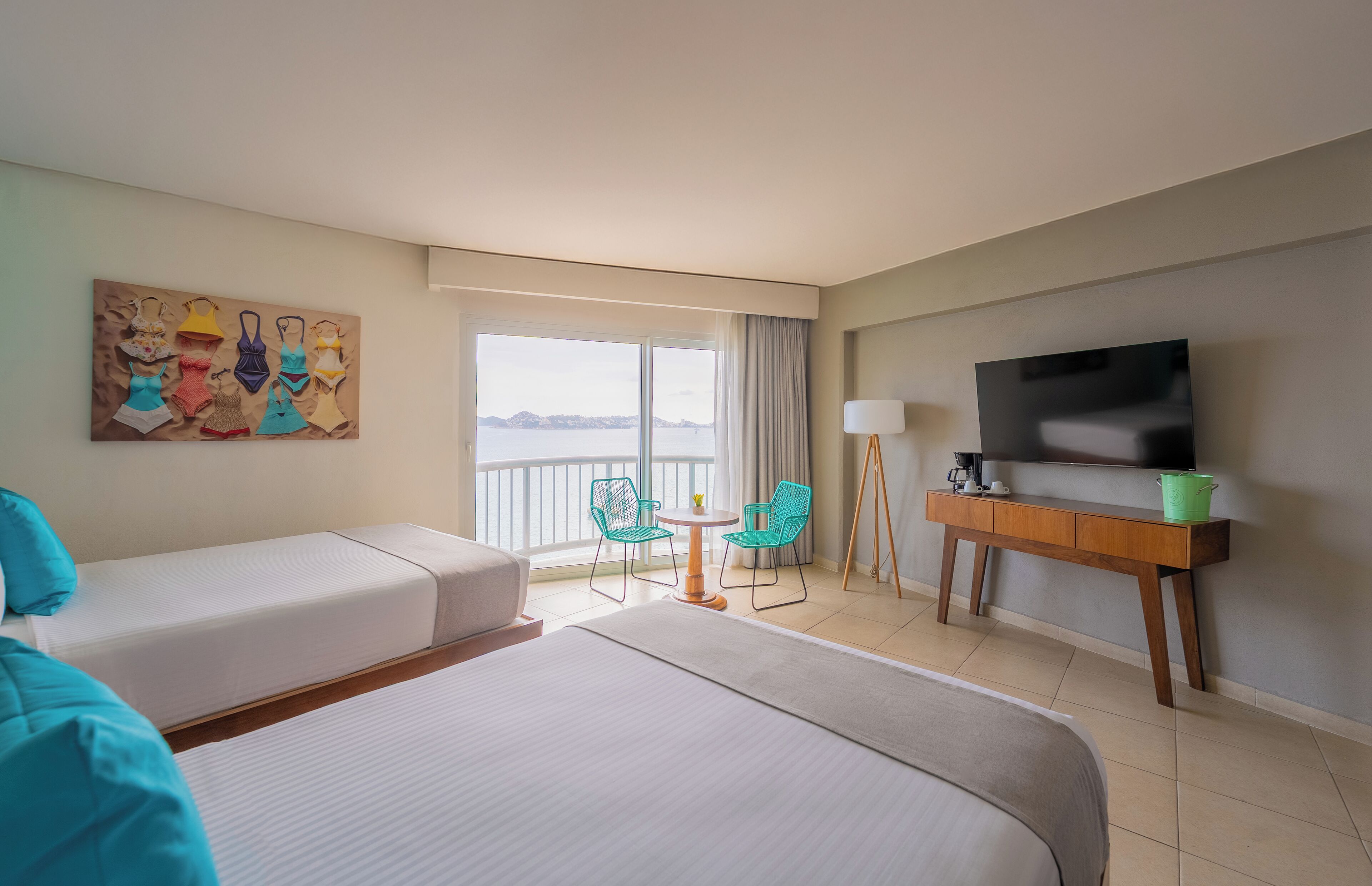 Ein Hotelzimmer mit einem großen Bett, einer Sitzecke, einem Fernseher, einem Gemälde, einem Balkon mit Aussicht und einem kleinen Tisch mit Stühlen.