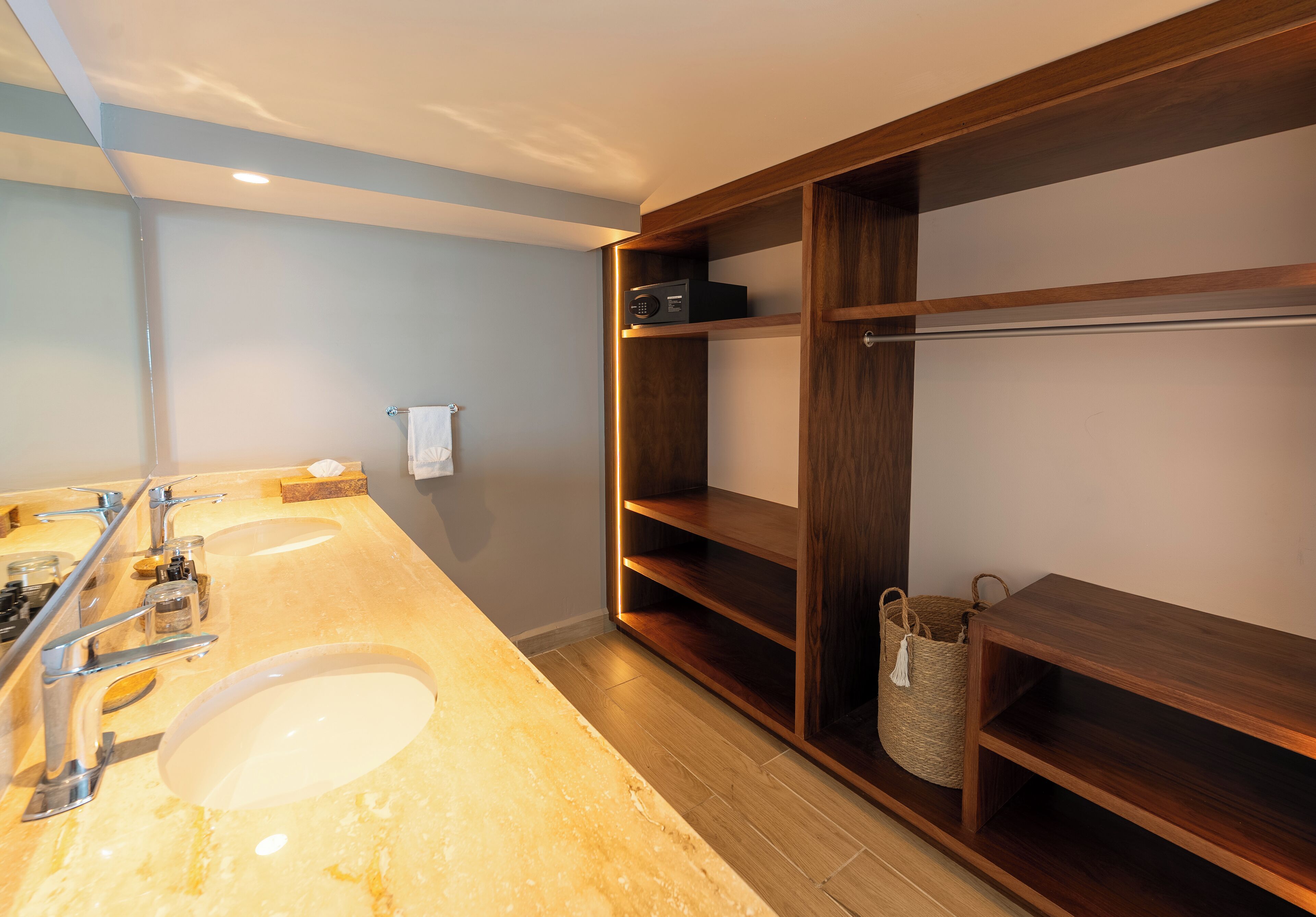 A bathroom with a marble sink, two faucets, a mirror, and a wooden vanity with shelves.