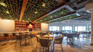 Zona de bar àmplia amb diverses opcions de seients i un gran finestral que aporta llum natural.