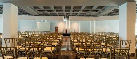 Un salón amplio con filas de sillas dispuestas para un evento.