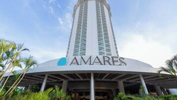 A tall hotel with a prominent 'AMARES' sign, featuring a modern design with a curved entrance and a central column.