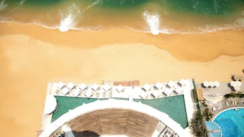 Rannalla, aurinkotuoleja, aurinkovarjoja, rantapyyhkeitä