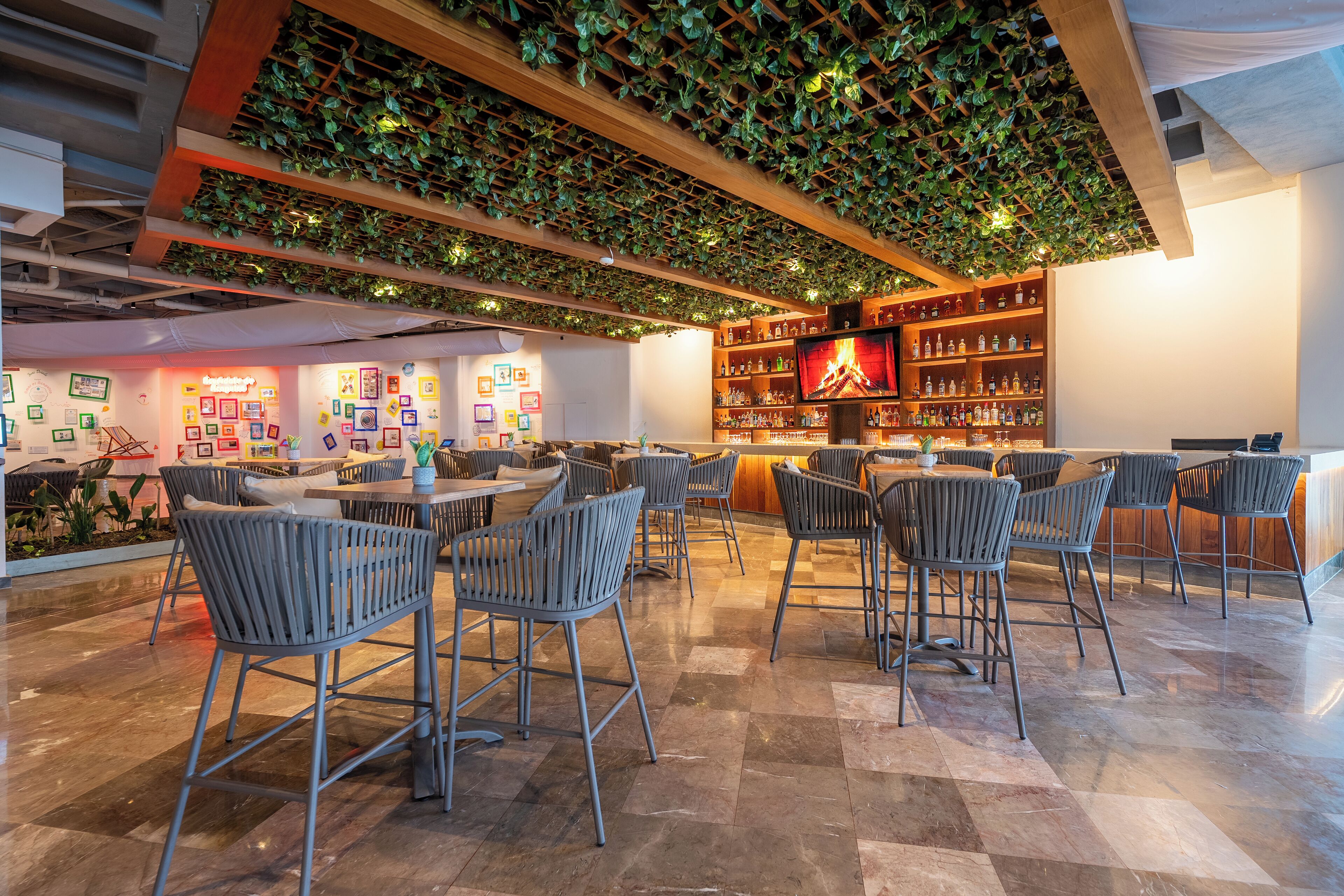 A modern bar area with a green living wall, multiple seating arrangements, and a well-stocked bar counter.