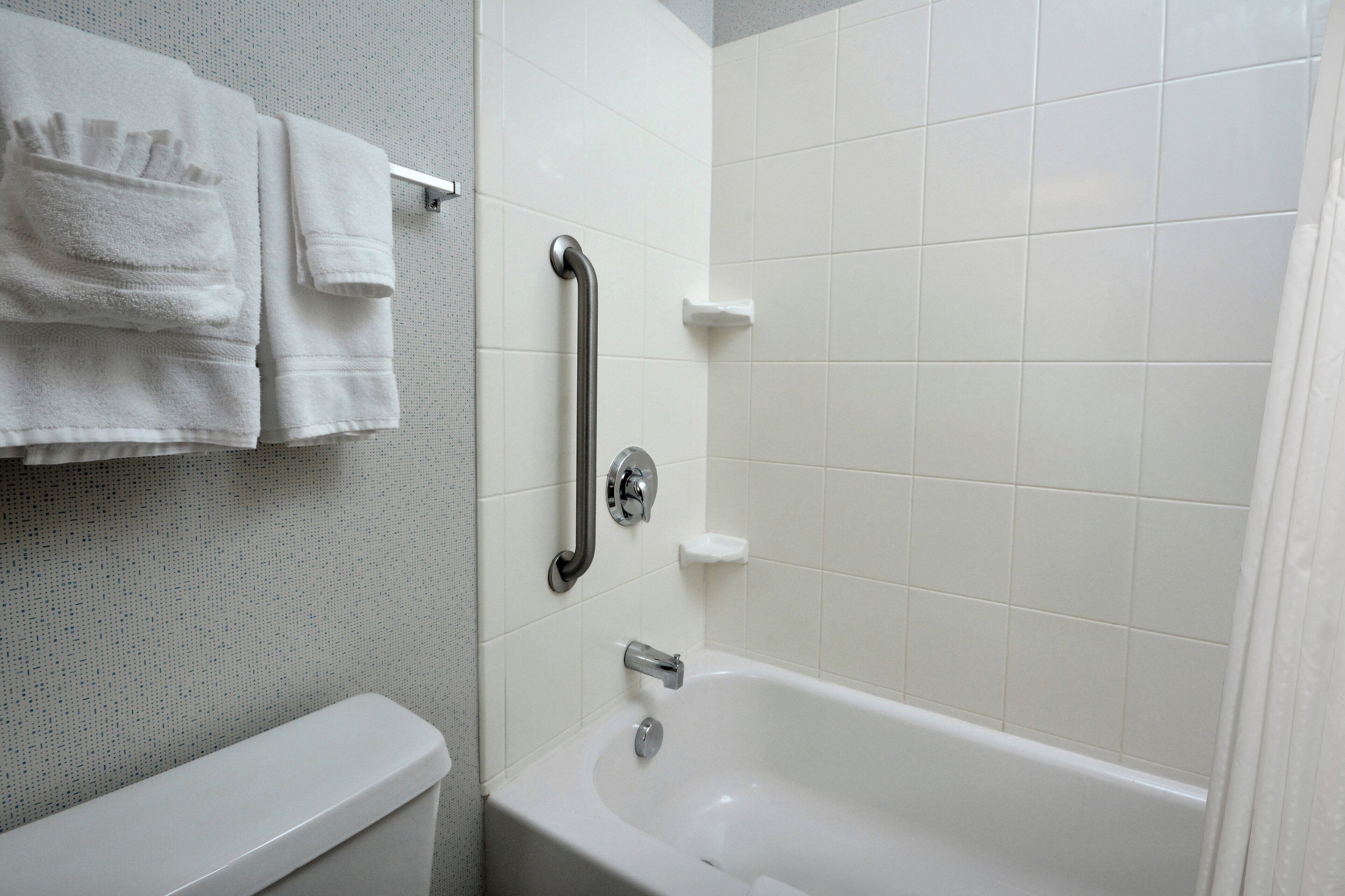 Une salle de bain avec une baignoire blanche, des toilettes et un porte-serviettes avec des serviettes pliées.