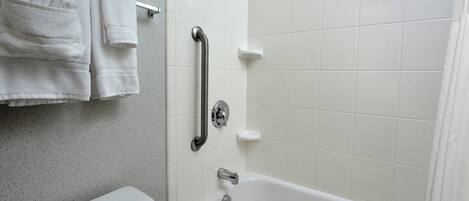 Une salle de bain avec une baignoire blanche, des toilettes et un porte-serviettes avec des serviettes pliées.