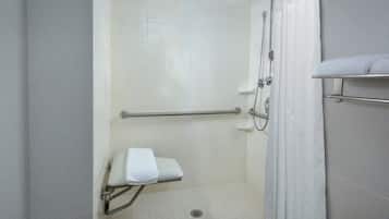 A walk-in shower with a grab bar, a white towel on a shelf, and a shower curtain.