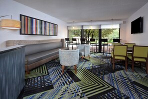 Eine moderne Lounge mit einer Couch, Sesseln, einem gemusterten Teppich und einem Fernseher.