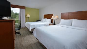 A hotel room with two beds, a TV, a desk, and a chair.