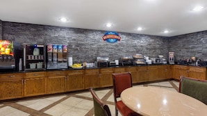 A breakfast area with a stone wall, wooden cabinets, a buffet counter, and a seating area with a table and chairs.