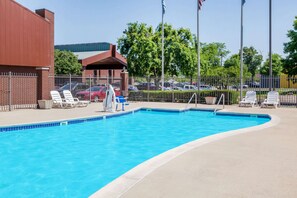 Une piscine avec des chaises longues et un parking en arrière-plan.