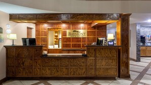 A reception desk with a wooden finish and a sign for Baymont Inn & Suites.